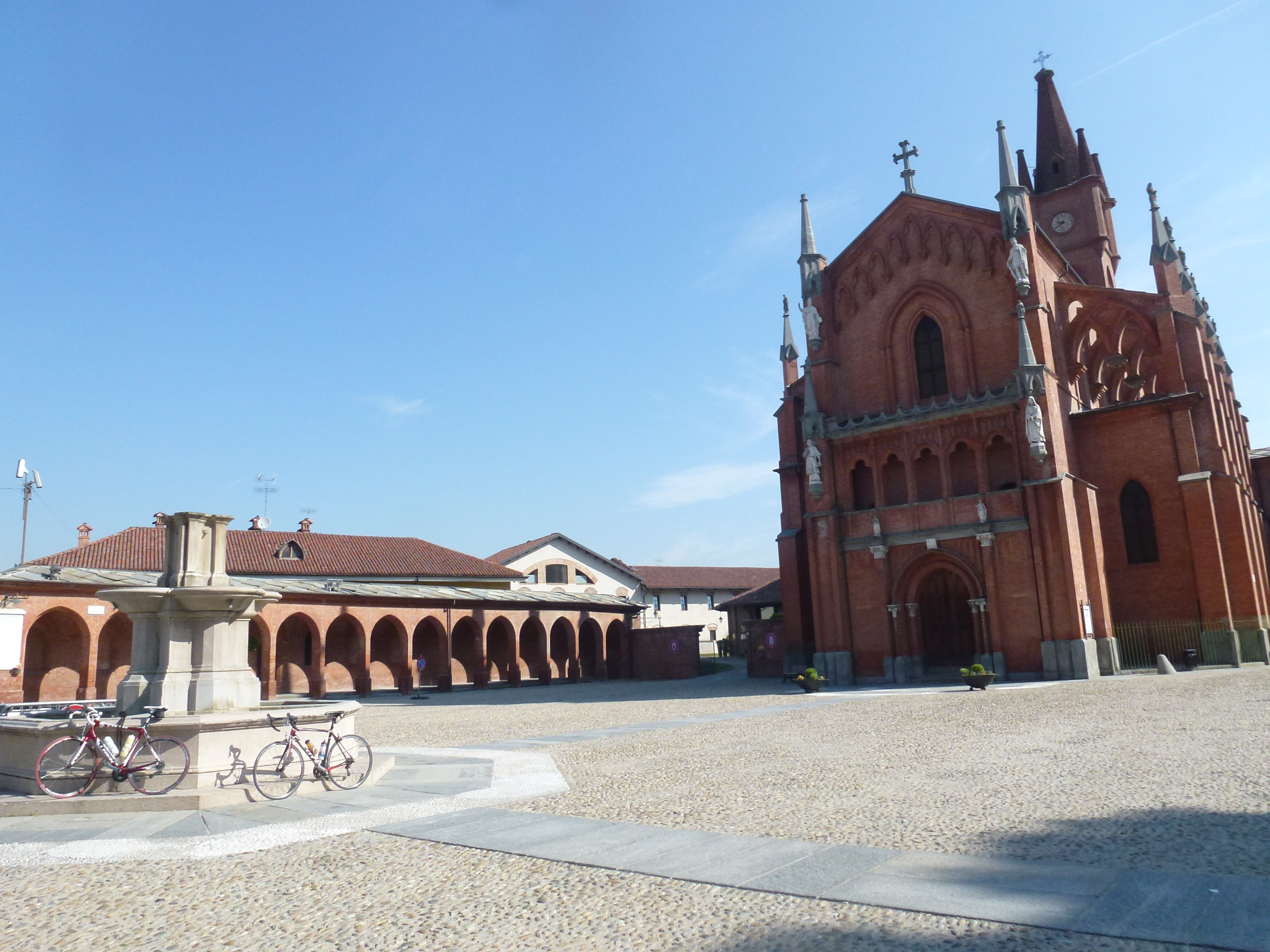 Cycle past the brick red gothic church in Pollenzo, Piedmont